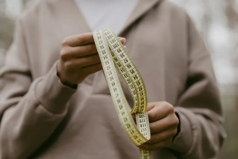 A person holding a measuring tape with blurred background outdoors